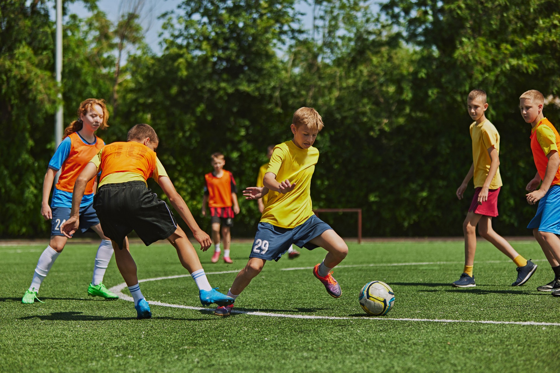 Teen boys in vibrant sports attire maneuver soccer ball with precision and speed, emphasizing teamwork and strategy. Outdoor game